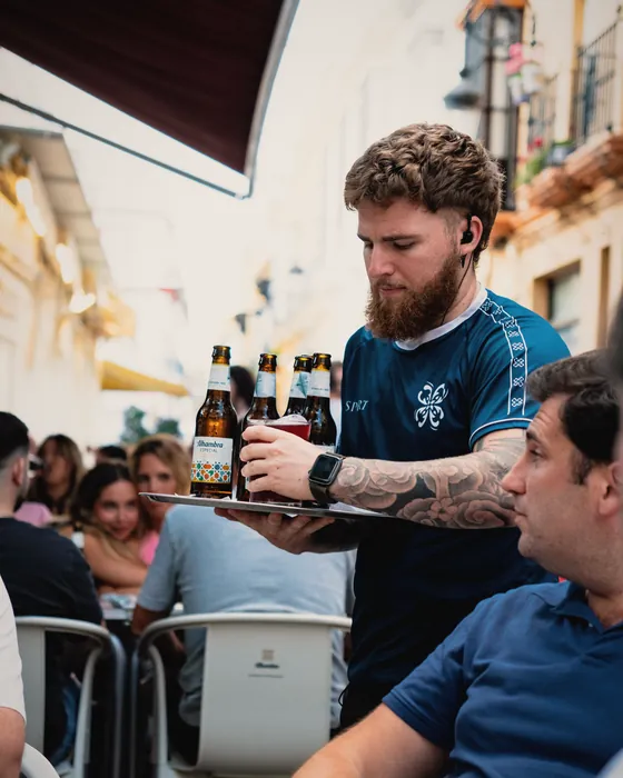 Camarero sirviendo botellines en la terraza llena