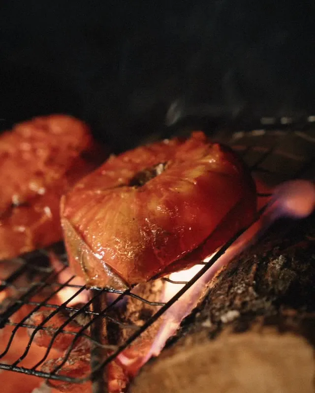 Tomates asándose sobre brasa de leña